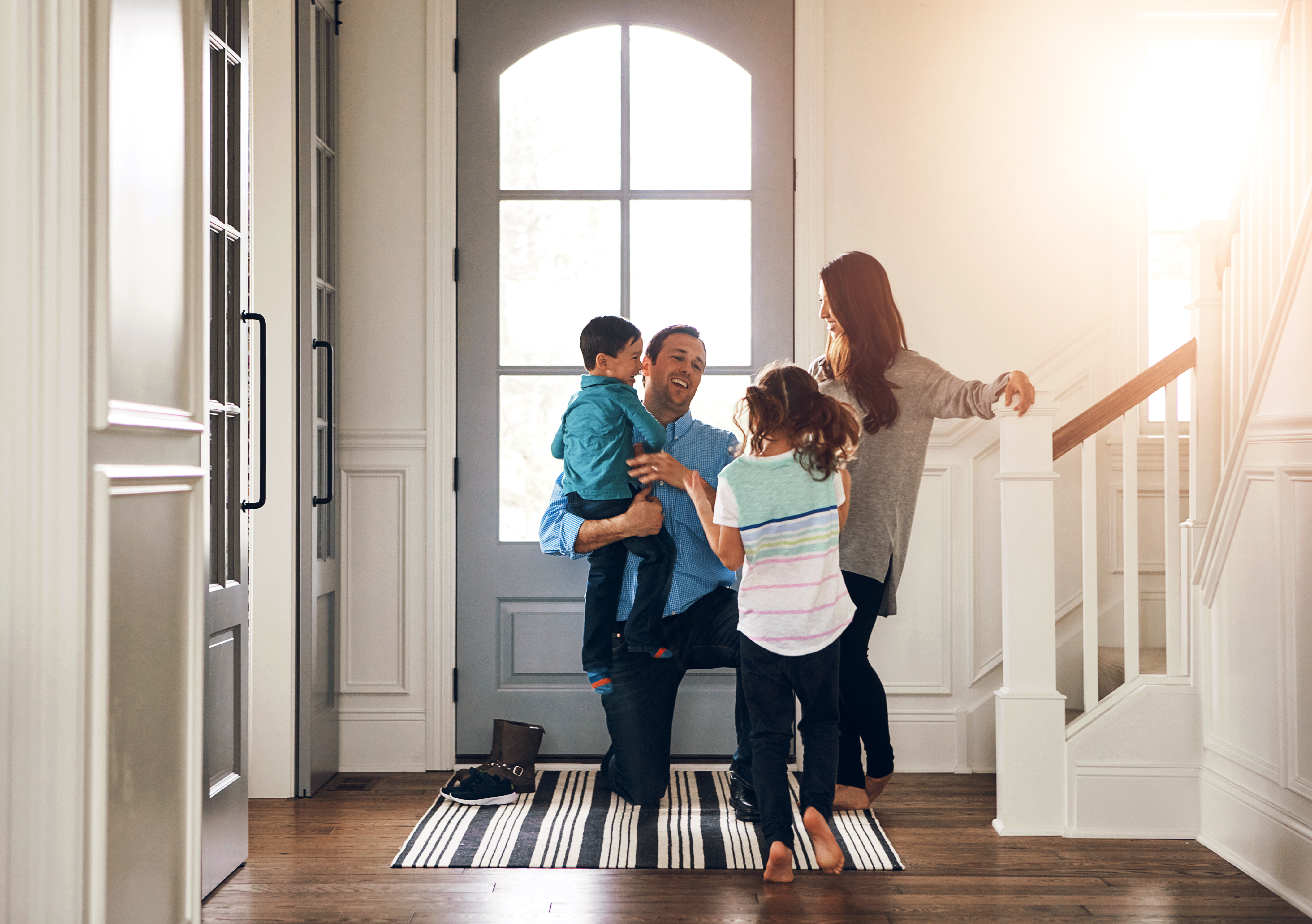 Happy door and parents with children hug in home
