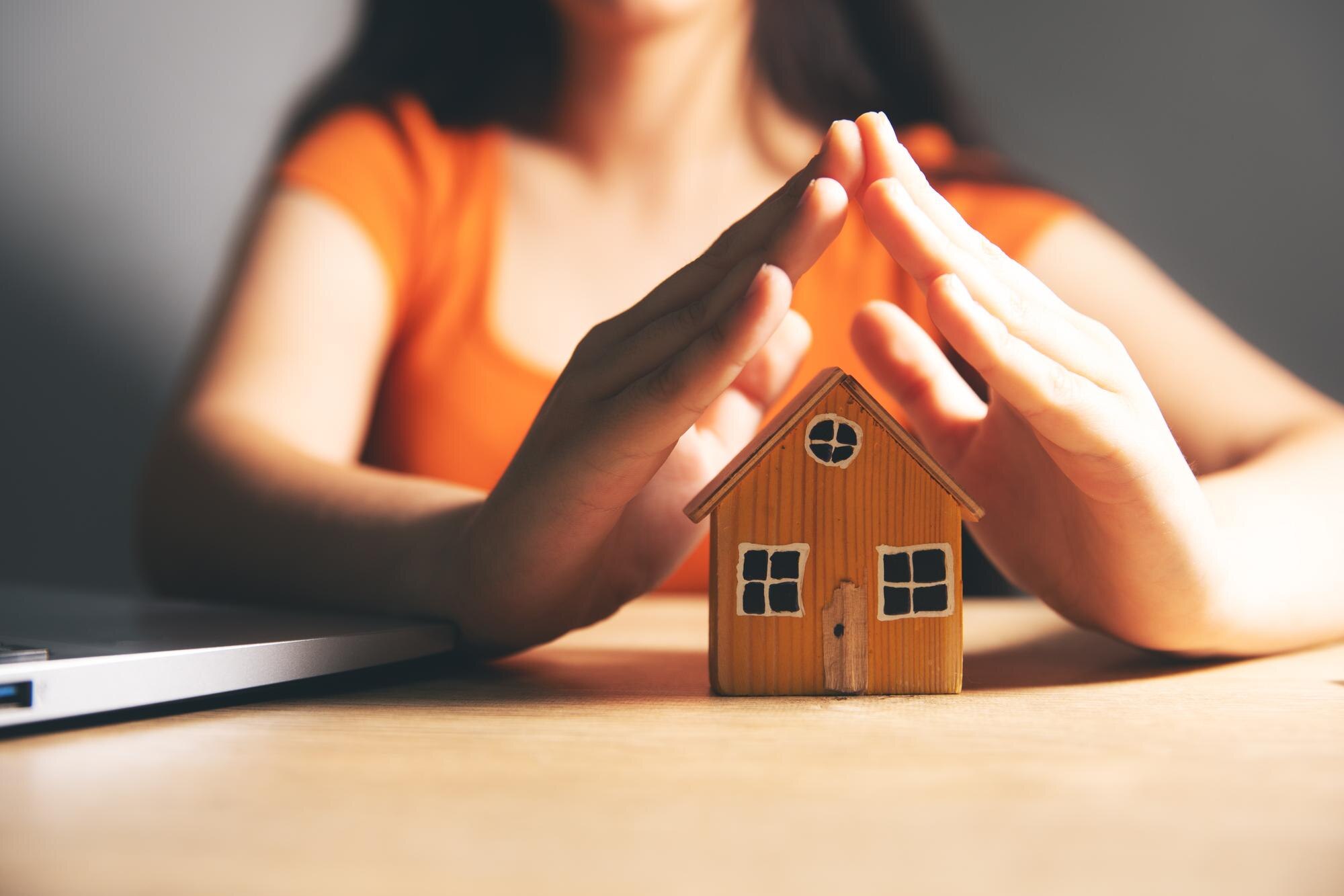 Woman hand holding house model with computer lapto