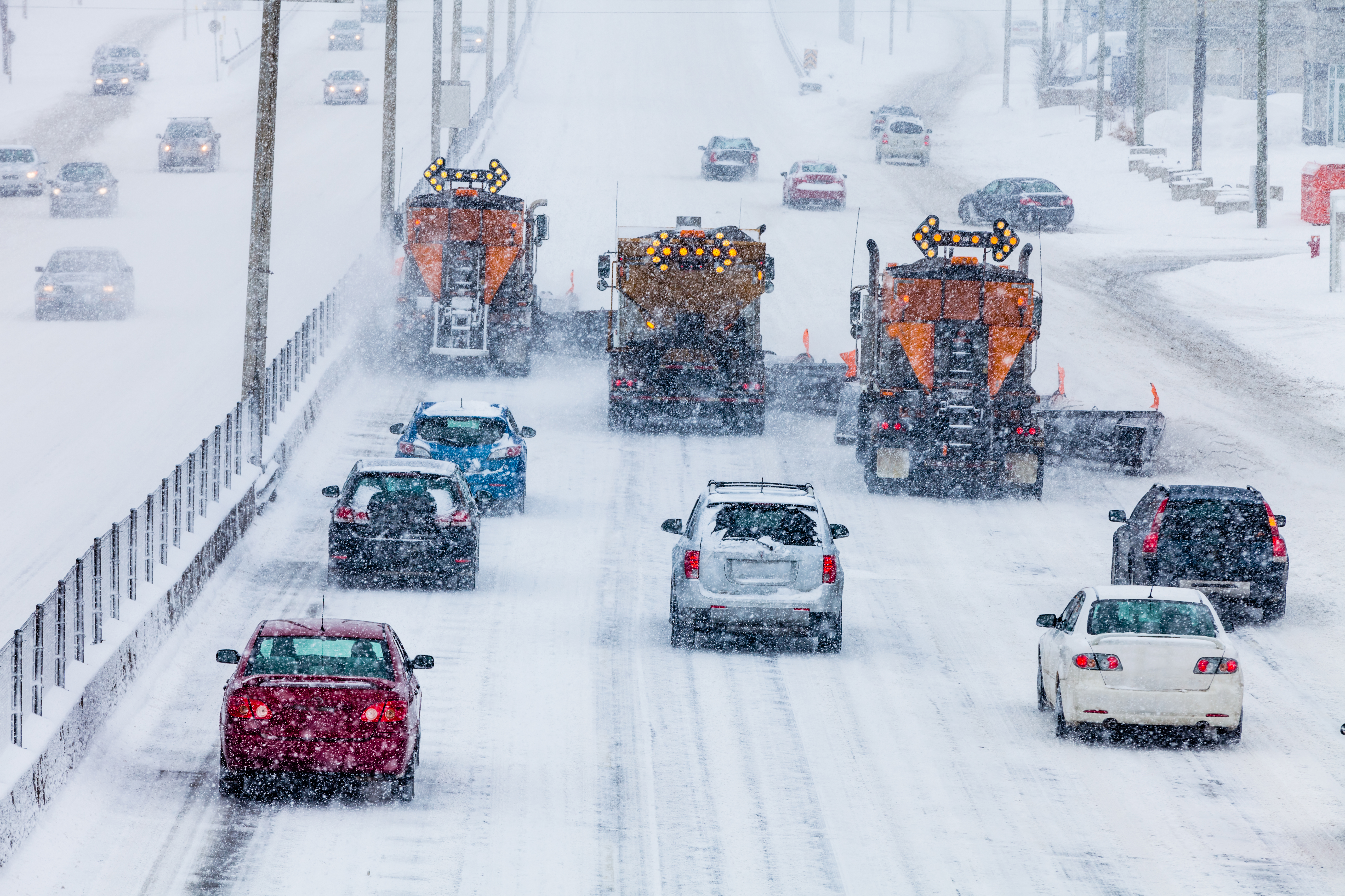 Tree lined up snowplows clearing the highway