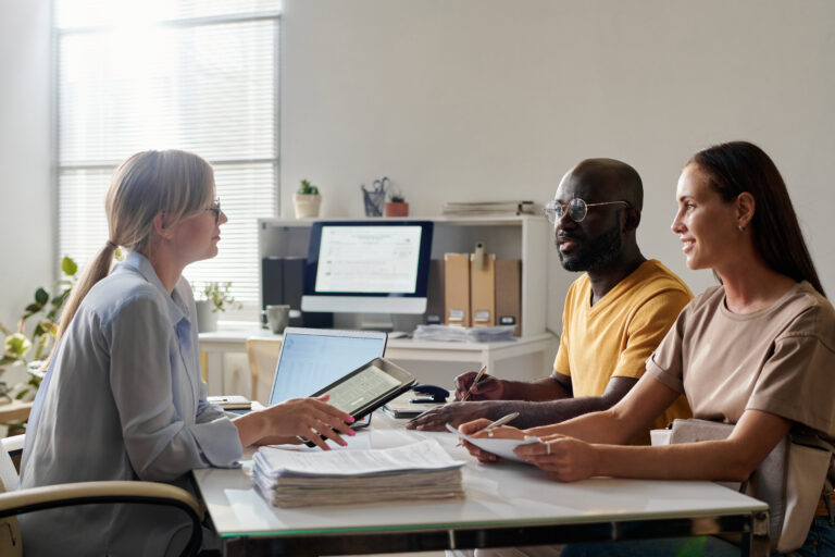A couple reviewing insurance paperwork with an advisor across a desk