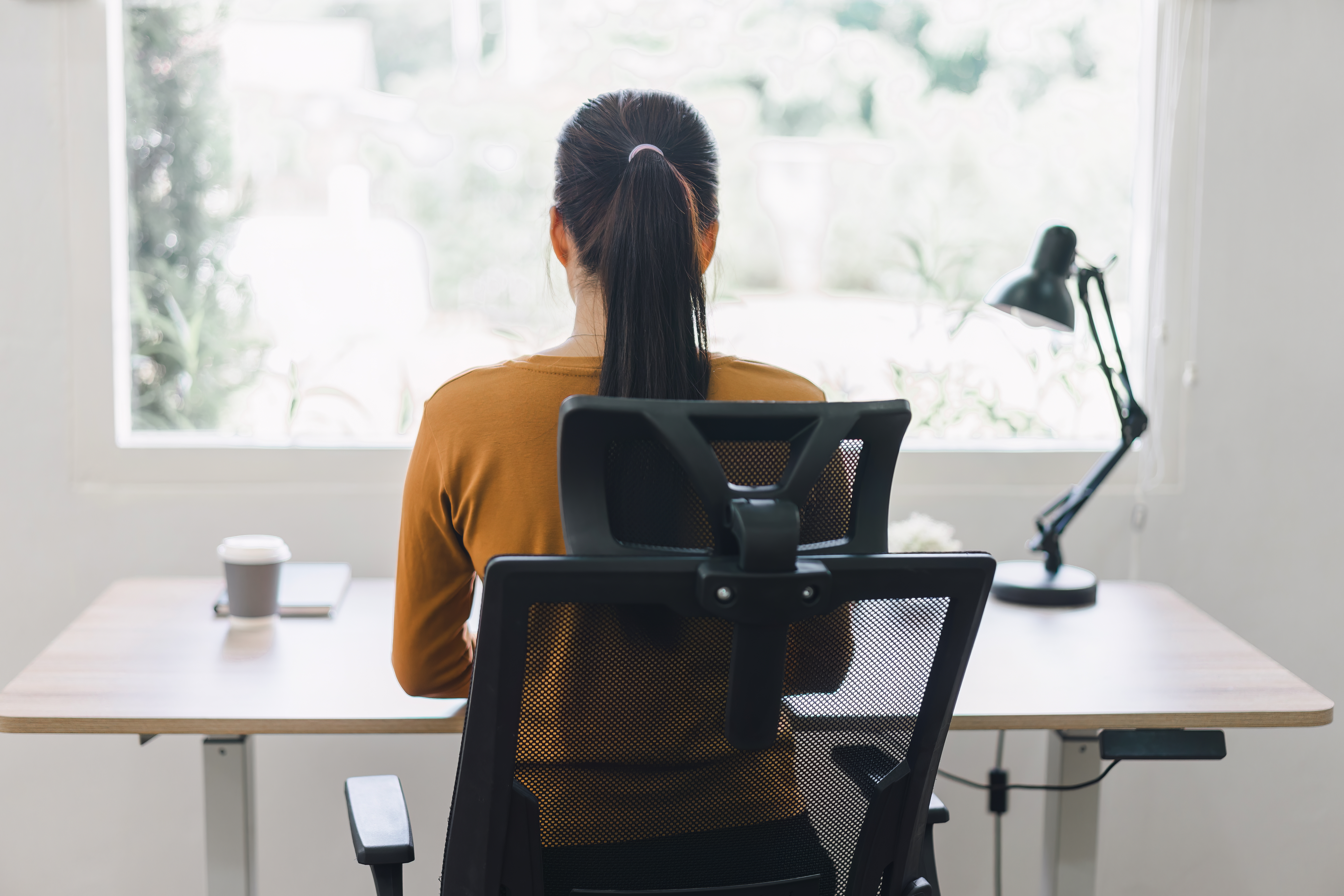 Rear view of woman sitting at desk working from