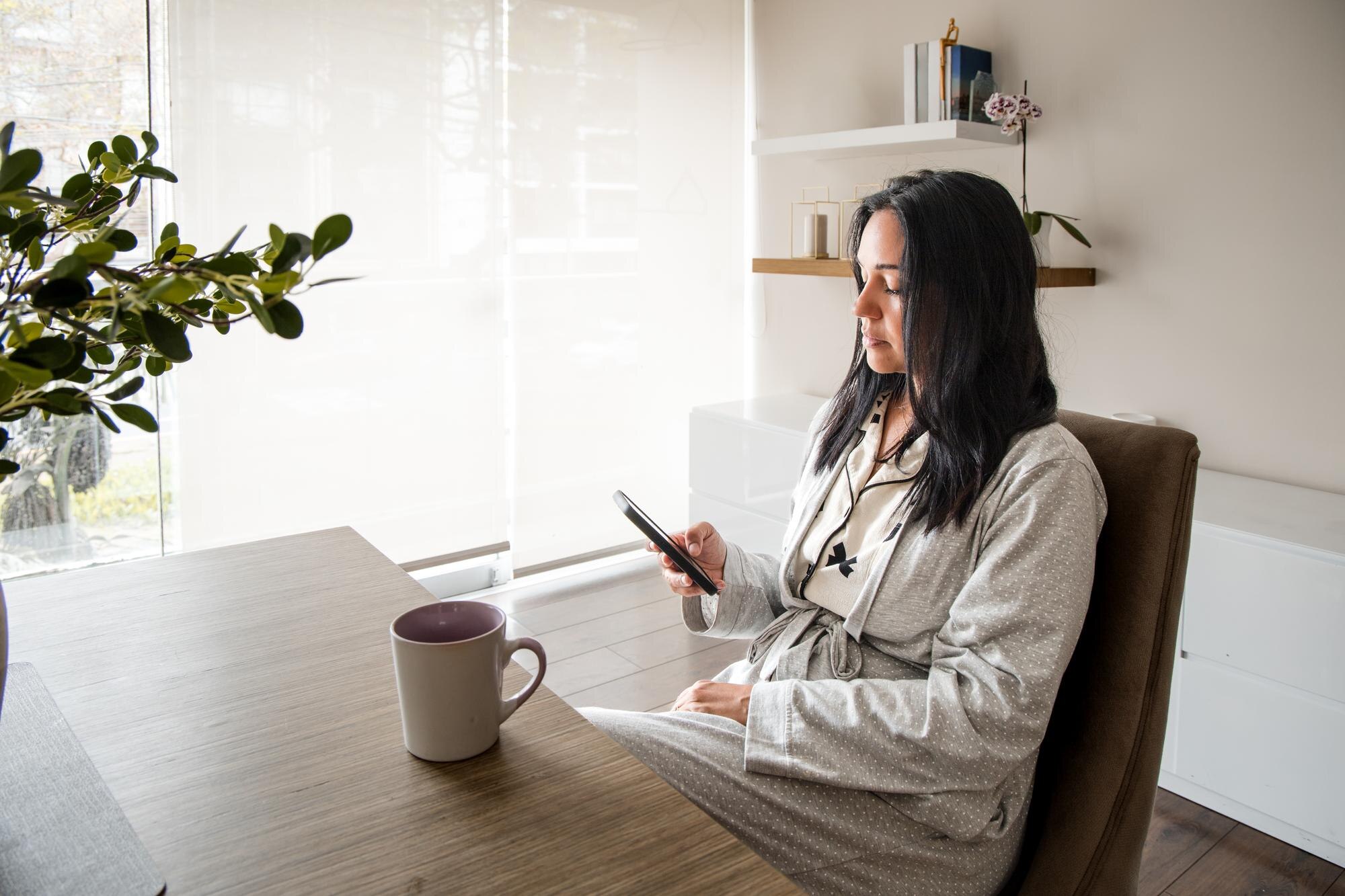 A woman is sitting at a table with a cell phone