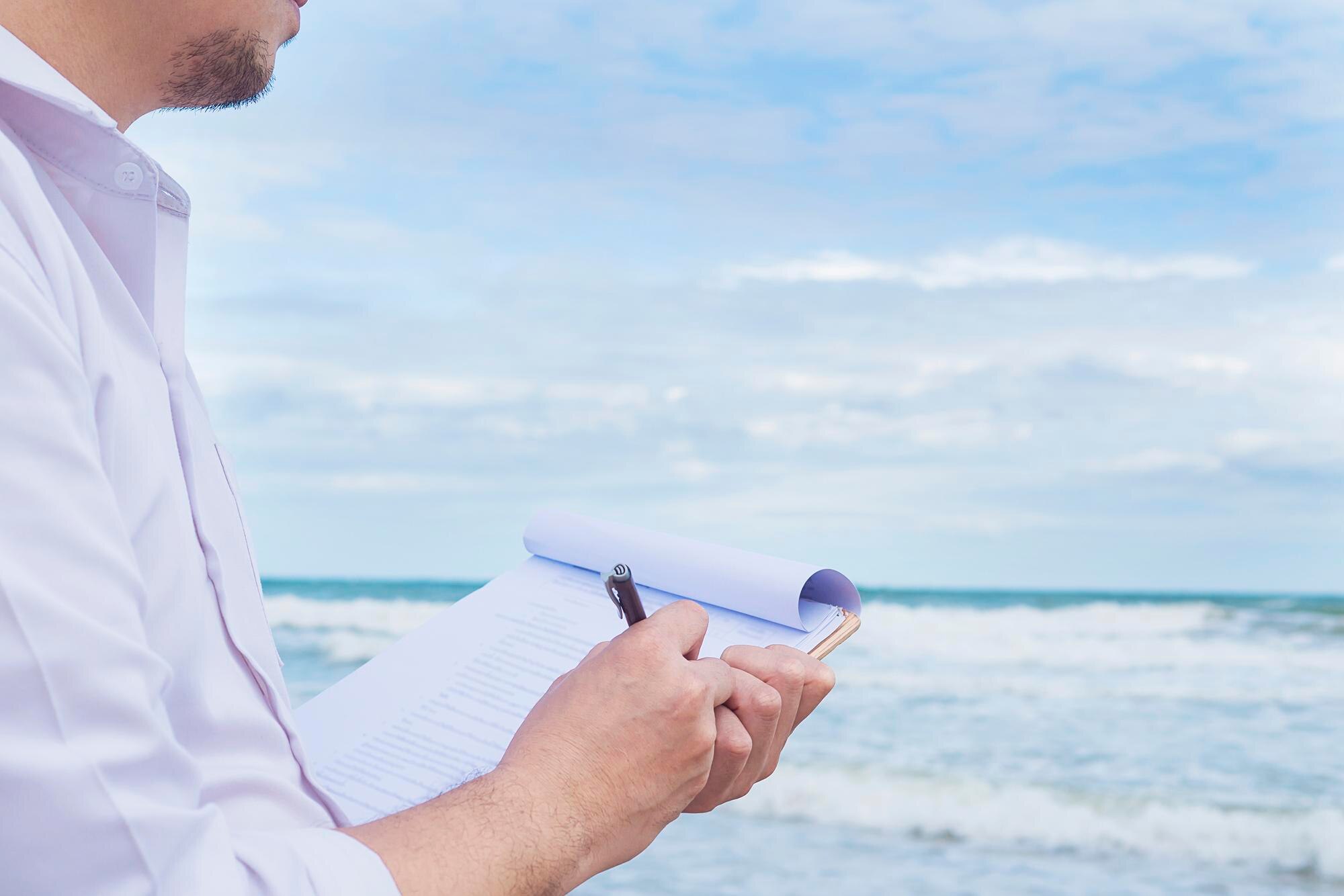 Midsection of man writing in book while standing
