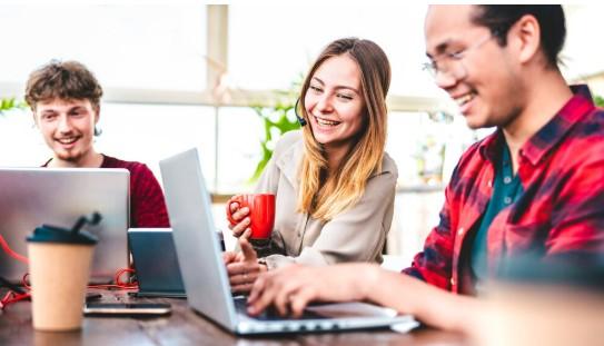 Gen Z employee working on a laptop with a colleague in a modern office