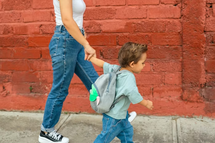 Working parent walking a child to school in the morning, symbolizing how family benefits like childcare support and flexible schedules reduce stress during the back-to-school season.